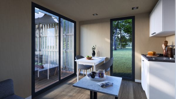 Intérieur lumineux d'un module en bois avec grande baie vitrée donnant sur une terrasse et vue sur un jardin arboré.