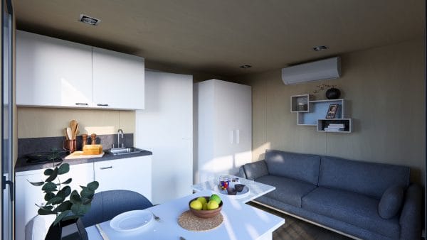 Intérieur moderne d'un module en bois avec espace de vie ouvert combinant cuisine blanche, coin repas et salon avec canapé gris