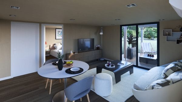 Intérieur moderne d'un module en bois avec espace salon-salle à manger lumineux, table ronde blanche, mobilier contemporain et vue sur terrasse extérieure.